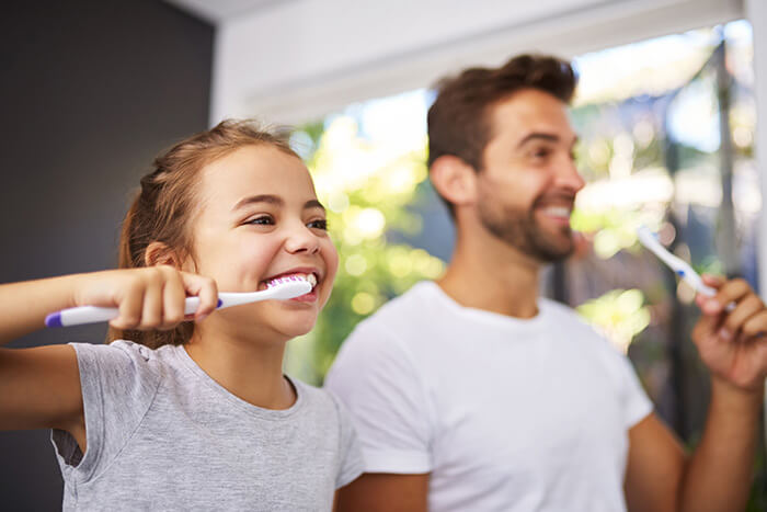father and daughter brushing teeth